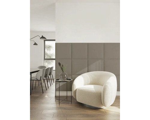 Modernes Wohnzimmer mit einer Wand aus beige-braunen, quadratischen Akustikpaneelen, einem cremefarbenen Sessel und einem Essbereich im Hintergrund.