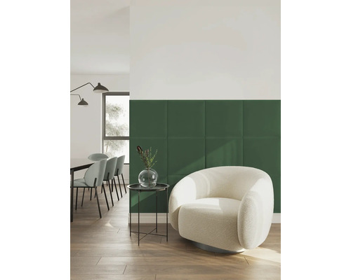 Modernes Wohnzimmer mit grünen Polsterpaneelen an der Wand, hellem Sessel, Beistelltisch und Essbereich auf Holzboden.