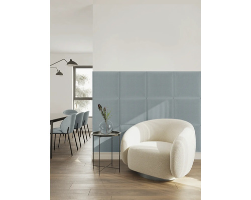 Quadratische gepolsterte Wandpaneele aus Stoff in Blau in einem hellen, modern eingerichteten Wohnzimmer mit weißem Sessel und Holzfußboden.