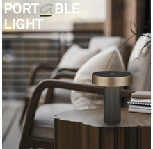 Lampe de table d extérieur portable et moderne sur une table d appoint en bois dans un balcon organisé avec des fauteuils et des coussins.