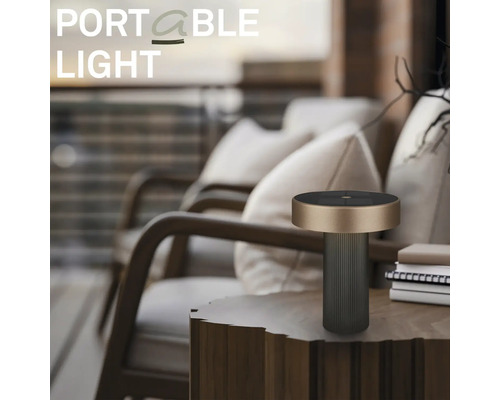 Lampe de table d extérieur portable et moderne sur une table d appoint en bois dans un balcon organisé avec des fauteuils et des coussins.