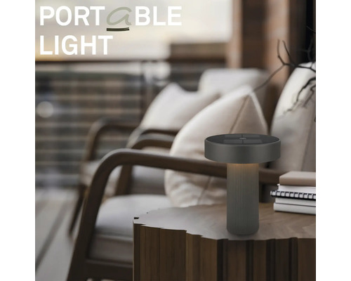 Lampe de table à LED portable moderne sur une table en bois dans un espace extérieur avec des fauteuils.