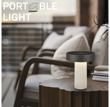 Lampe de table à LED portable sur une table en bois dans un espace extérieur moderne avec des fauteuils confortables.