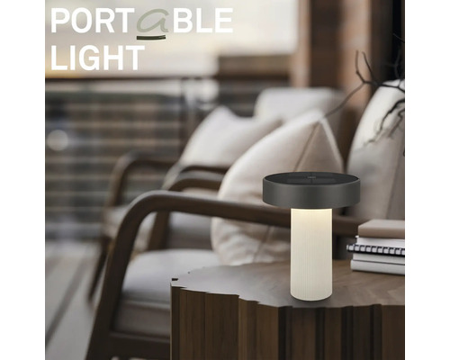Lampe de table à LED portable sur une table en bois dans un espace extérieur moderne avec des fauteuils confortables.