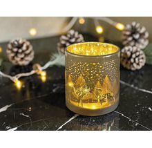 Windlicht aus Glas mit Hirsch-Motiv und Winterlandschaft, beleuchtet zwischen Weihnachtsdekoration wie Tannenzapfen.