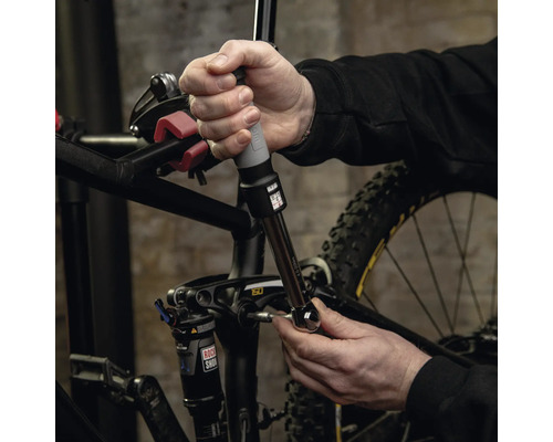Eine Person verwendet einen Drehmomentschlüssel zur Einstellung von Schrauben an einem Mountainbike.