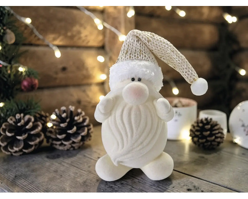 Dekorative Weihnachtsmann-Figur mit glitzernder Strickmütze und Wellenbart in einer weihnachtlichen Szene mit Zapfen und Lichterketten.
