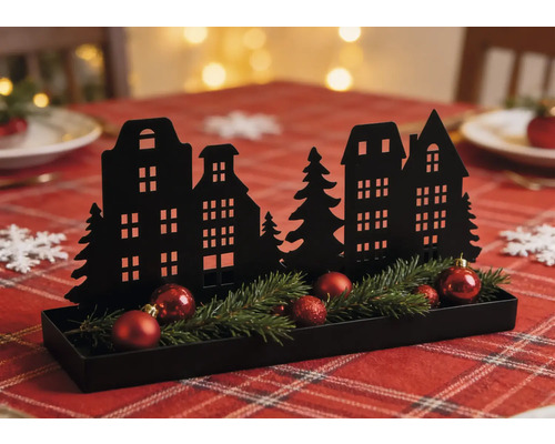 Schwarze Weihnachtsdekoration aus Metall mit Häusersilhouette, Tannengrün und roten Kugeln in einem Tablett auf einem festlich gedeckten Tisch.