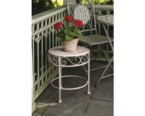 Runder Garten-Beistelltisch aus Metall mit dekorativen Verzierungen und einem Blumentopf auf einer Terrasse mit Geländer.