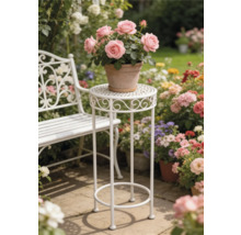 Weißer Pflanzenständer aus Metall und weiße Gartenbank in einem hellen Garten mit Blumen auf einer Steinterrasse.