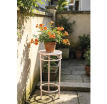 Hoher Blumenhocker aus Metall mit einer blühenden Klettertrompete im Tontopf auf einer hellen Terrasse.