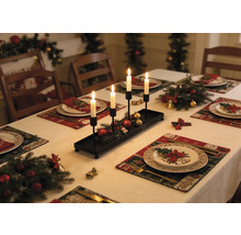 Schwarzer länglicher Kerzenhalter aus Metall mit vier weißen Kerzen auf einem festlich gedeckten Weihnachtstisch mit Tannenzweigen.