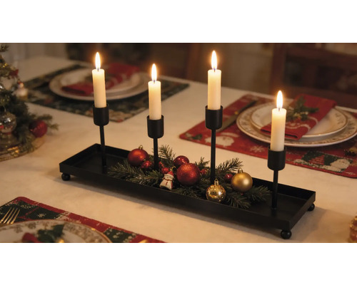 Adventskerzenhalter aus schwarzem Metall mit vier Kerzenhaltern, dekoriert mit Tannengrün und Weihnachtskugeln auf einem festlich gedeckten Tisch.