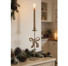 Hoher Metallkerzenständer mit Schleifenmotiv auf einer Ablage mit Tannenzweigen und Tannenzapfen.