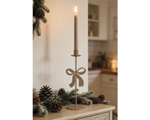 Hoher Metallkerzenständer mit Schleifenmotiv auf einer Ablage mit Tannenzweigen und Tannenzapfen.