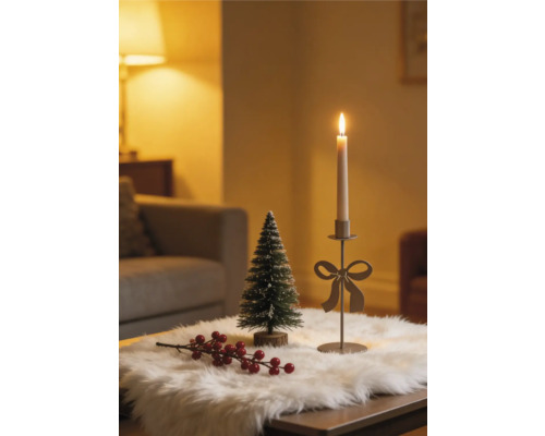 Weihnachtliche Tischdekoration mit Kerzenhalter mit Schleife, kleiner Tanne und roten Beeren auf weißem Kunstfell.
