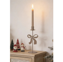 Eleganter Metall-Kerzenständer mit dekorativer Schleife, arrangiert mit Weihnachtsfiguren auf einer hellen Holzoberfläche.