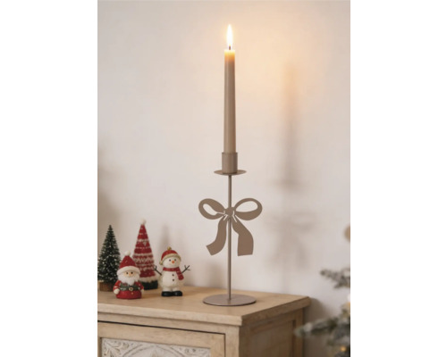 Eleganter Metall-Kerzenständer mit dekorativer Schleife, arrangiert mit Weihnachtsfiguren auf einer hellen Holzoberfläche.
