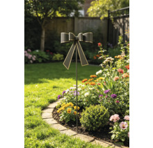 Dekorativer Gartenstecker aus Metall mit Schleife in einem sonnigen Blumenbeet mit bunten Pflanzen und angrenzendem Rasen.