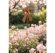 Dekorativer Gartenstab mit brauner Schleife und goldenem Rand in einem Blumenbeet mit rosa Blüten.