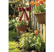 Gartenstecker mit roter Schleife und Goldrand in einem sonnigen Garten mit Tulpen und einem geflochtenen Korb.
