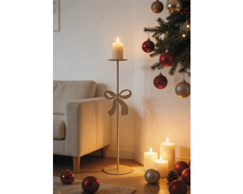 Hoher Kerzenständer mit Schleife in einer weihnachtlich dekorierten Wohnzimmerecke neben einem Sofa und beleuchteten Stumpenkerzen.