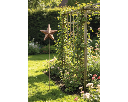 Gartenstecker Stern aus Metall in Rost-Optik in einem hellen Garten neben einem Holz-Rankgitter mit Kletterpflanzen und Blumenbeet.