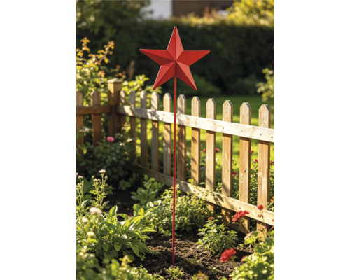Roter Gartenstecker in Sternform aus Metall in einem Blumenbeet vor einem hölzernen Lattenzaun.