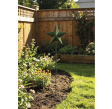 Gartenstecker aus Metall mit einem Stern in einem bepflanzten Blumenbeet vor einem Holzzaun.