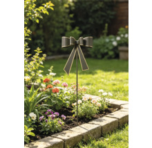 Gartenstecker in Form einer Schleife mit Goldkanten in einem bepflanzten Blumenbeet mit Natursteineinfassung.