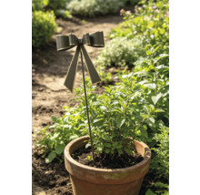 Gartenstecker mit einer Schleife in einem bepflanzten Terrakotta-Topf in einer grünen Gartenumgebung.