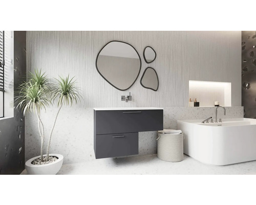 Salle de bain moderne avec meuble sous-vasque anthracite asymétrique, trois miroirs de forme organique, une baignoire blanche et une plante.
