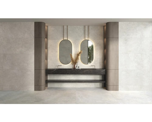Salle de bains moderne avec carrelage mural aspect pierre claire, double vasque aspect marbre noir et deux miroirs ovales rétroéclairés.