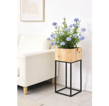 Moderner Blumenständer mit quadratischem Holz-Pflanzkasten auf schwarzem Metallgestell in einem hellen Wohnzimmer.