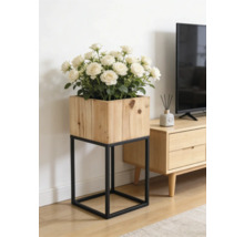 Quadratischer Pflanzkasten aus Holz auf einem schwarzen Metallgestell mit weißen Rosen in einem hellen Wohnzimmer neben einem TV-Board.