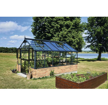 Großes Gewächshaus aus Glas und Metall auf einem Backsteinsockel mit geöffneten Dachfenstern in einem weitläufigen Garten am See.