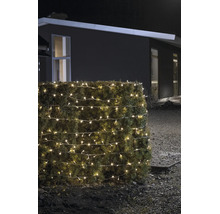 Warmweiss leuchtende LED-Lichterkette für den Außenbereich, um eine Hecke gewickelt, bei Nacht vor einem modernen Haus.