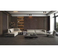Salon moderne avec carrelage sombre aspect marbre au sol et aux murs, canapé d'angle beige et étagères intégrées éclairées.