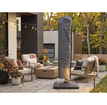 Housse de protection grise pour parasol déporté sur une terrasse moderne avec salon de jardin, table de foyer et guirlande lumineuse.