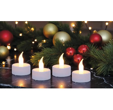 Vier weiße LED-Teelichter mit warm leuchtenden Flammen auf einer dunklen Marmoroberfläche, festliche Weihnachtsdekoration im Hintergrund.