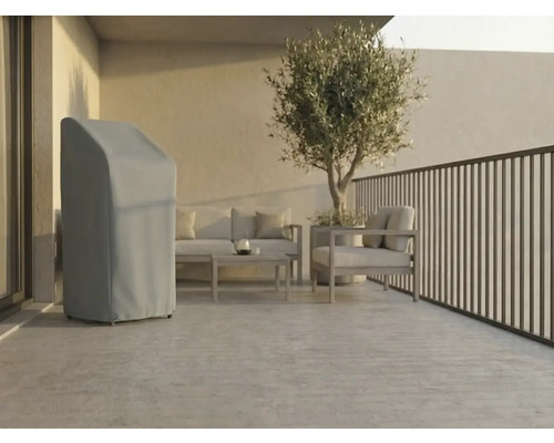 Terrasse moderne et lumineuse avec une housse de protection grise pour matériel de jardin, des meubles de salon en métal et un olivier en pot.