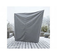 Graue Schutzhülle für einen Strandkorb auf einer verschneiten Holzterrasse im Garten.