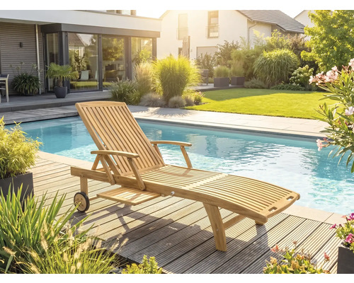 Gartenliege aus Teakholz mit Rollen und Ausziehtisch auf einer Holzterrasse an einem Pool in einem hellen Garten.