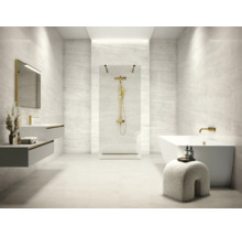Salle de bains moderne avec carrelage aspect pierre, douche italienne, robinetterie dorée, baignoire îlot et double vasque suspendue.