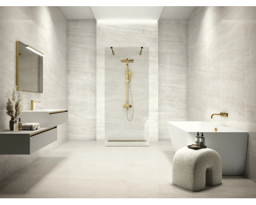 Salle de bains moderne avec carrelage aspect pierre, douche italienne, robinetterie dorée, baignoire îlot et double vasque suspendue.