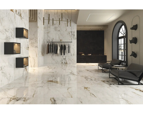 Intérieur moderne avec des carreaux en grès cérame grand format aspect marbre au mur et au sol, espace de vente élégant avec fauteuils.