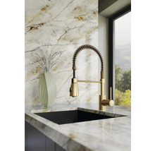 Moderne Küchenarmatur mit Spiralfeder und Ausziehbrause, Einhandmischer in Gold-Optik, montiert auf einer hellen Marmor-Arbeitsplatte.