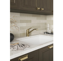 Moderne Küchenarmatur in Gold-Optik an einer Spüle mit Marmor-Arbeitsplatte und länglichen Wandfliesen.