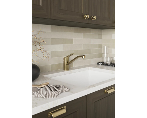 Moderne Küchenarmatur in Gold-Optik an einer Spüle mit Marmor-Arbeitsplatte und länglichen Wandfliesen.