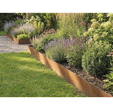 Bordure de jardin en acier Corten séparant la pelouse d une plate-bande plantée de graminées et de plantes vivaces.